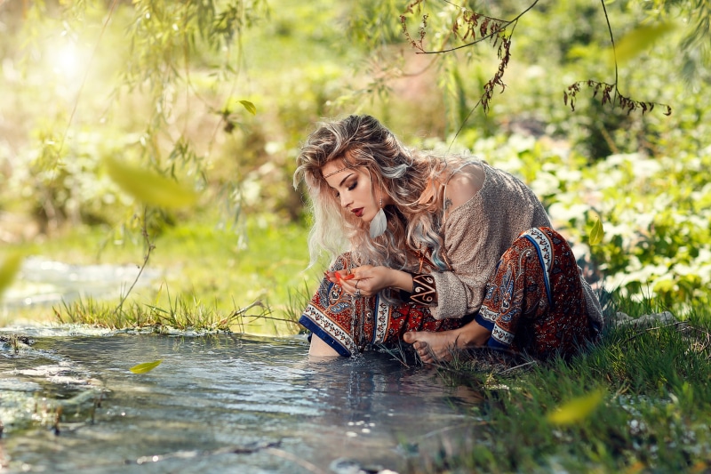 Woman sitting by a stream with leaves