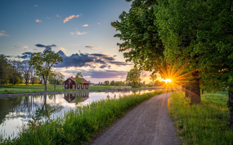 Sunset over canal with red house and sun rays