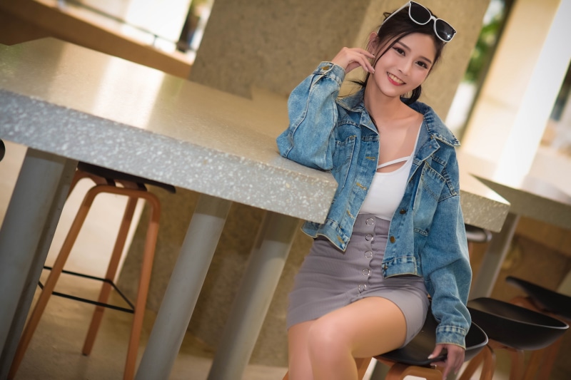 Asian woman in denim jacket and skirt posing