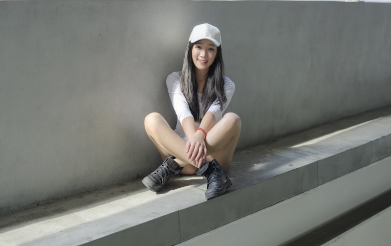 Asian girl in baseball cap sitting