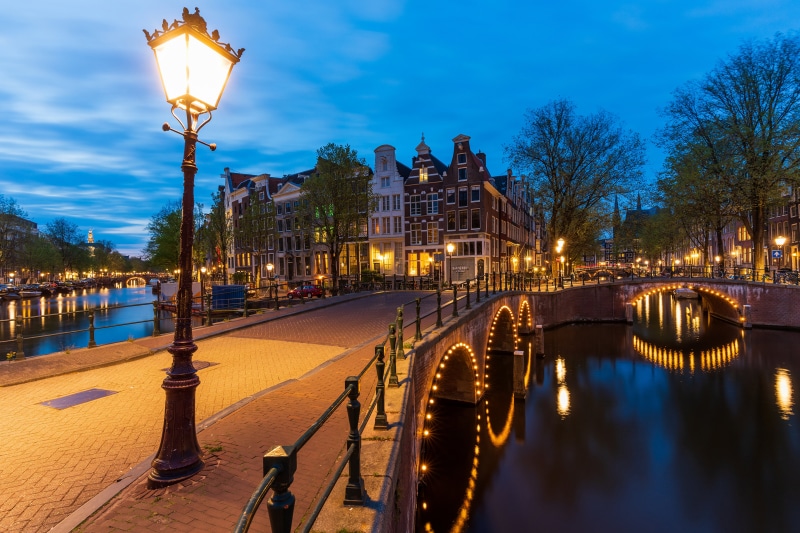 Amsterdam canal with bridges and street lights at dusk
