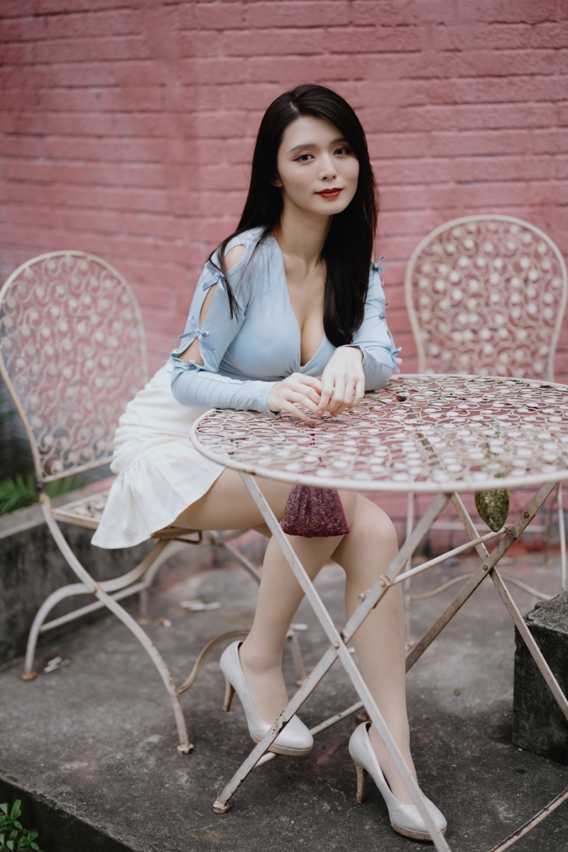 Woman in light blue top and white skirt sitting at table