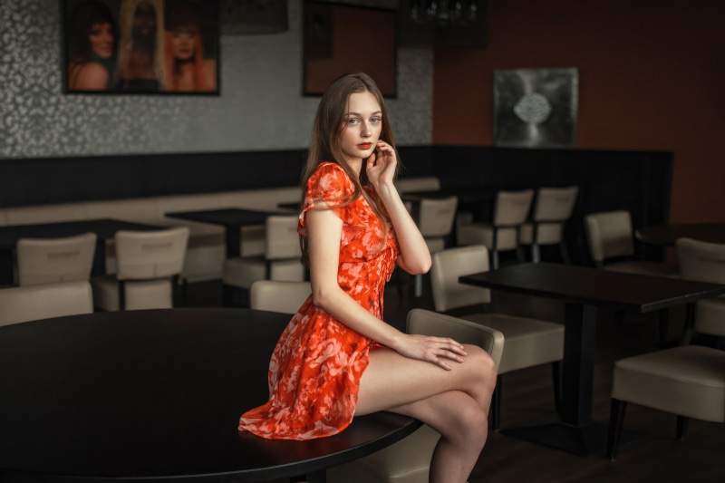 Model in orange dress sitting at table