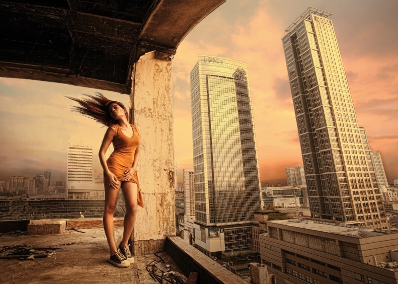 Model on a rooftop with city skyline at sunset