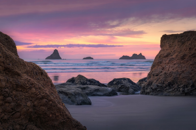 Beach at dawn with rock formations and colorful sky