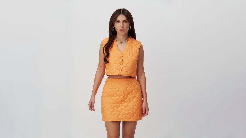 Woman in orange quilted vest and skirt