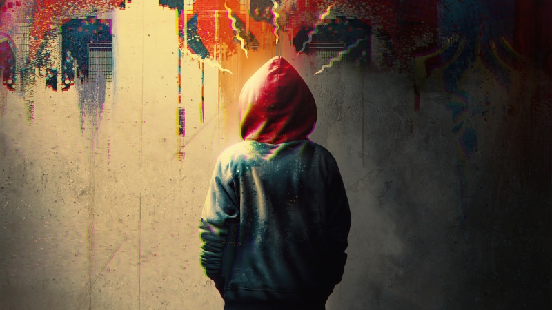Person in hoodie with red hood against abstract graffiti wall
