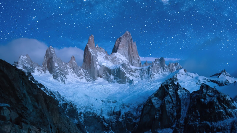 Snowy mountains under a starry night sky