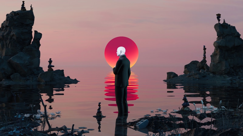 Man in suit facing sunset over water