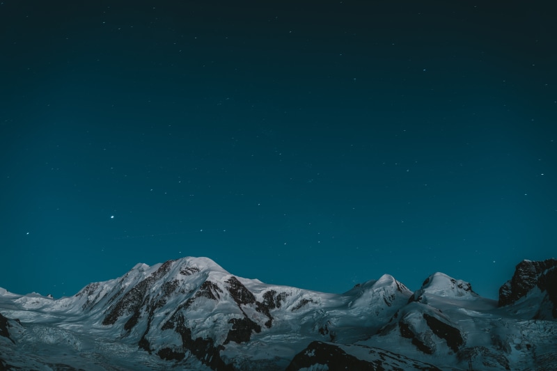 Snowy mountains under a starry night sky