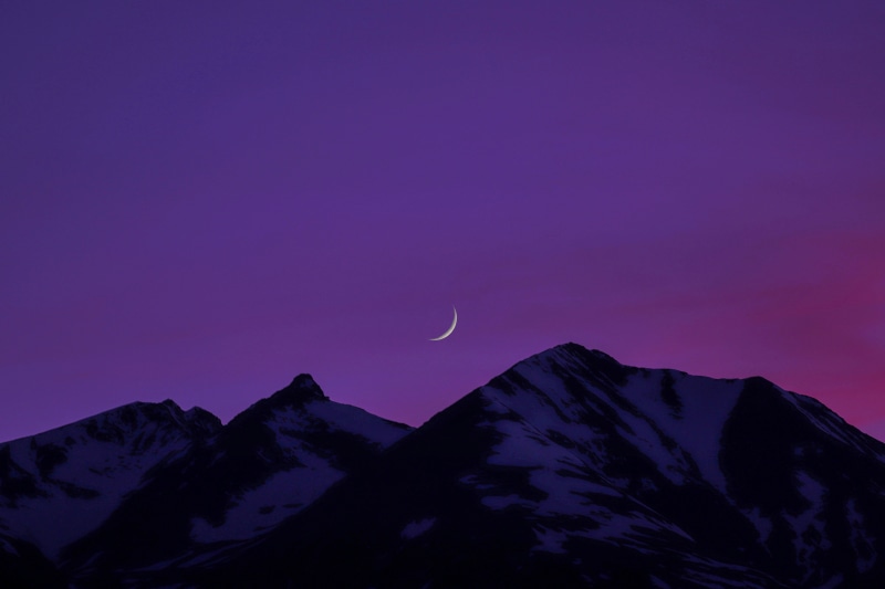 Minimalist mountain range with crescent moon at dusk