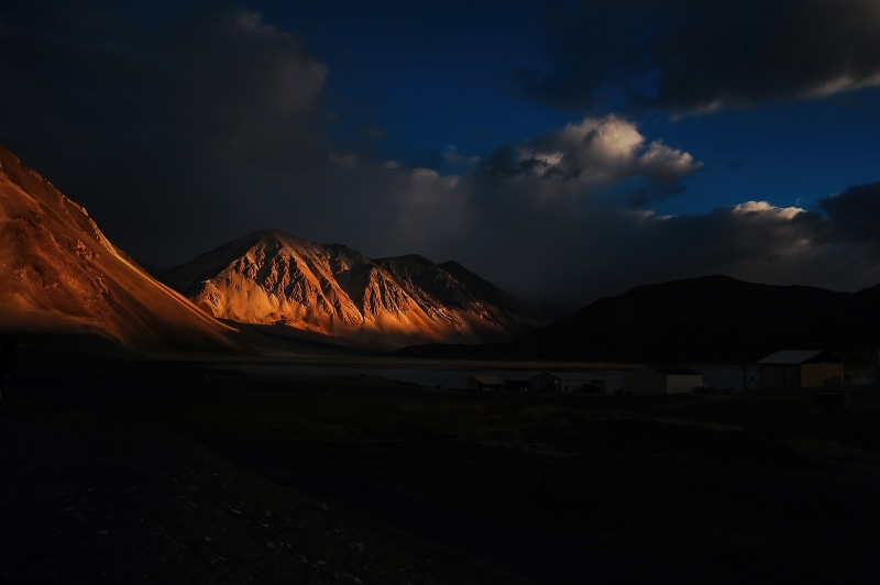 Mountains illuminated by sunset with dark clouds