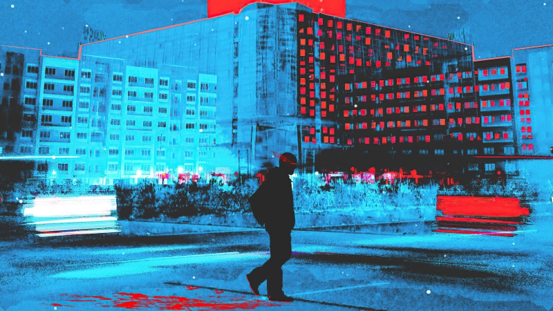 Man walking in front of apartment buildings at night