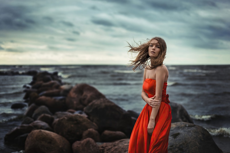 Girl in orange dress on rocky shore