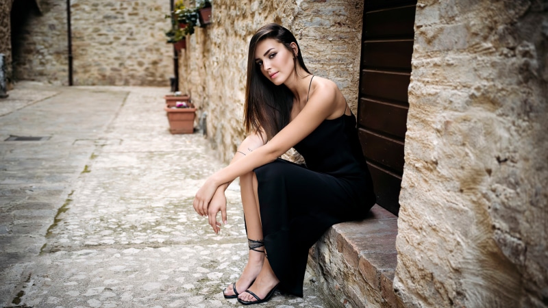 Model in black dress sitting on stone steps