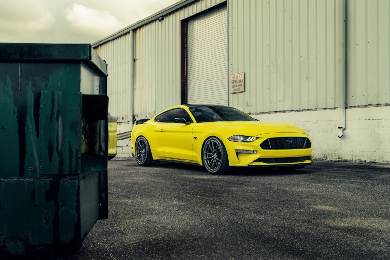 Yellow Ford Mustang GT parked near a building
