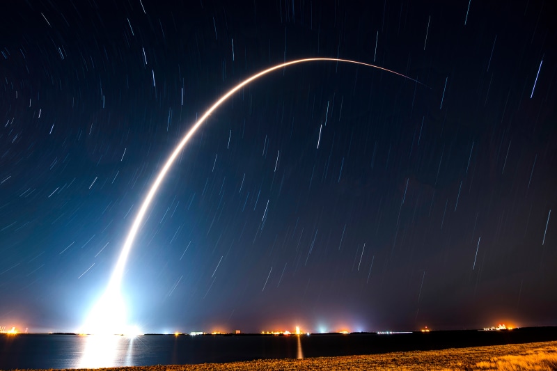 SpaceX rocket launch trail over ocean at night