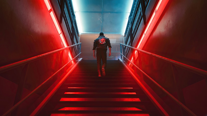 Man in Samurai jacket walks up red lit stairs