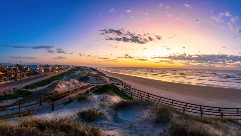 Sunset over a beach with sand dunes and boardwalk