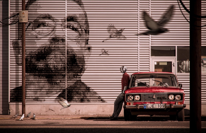 Artwork of a man and a red car with birds