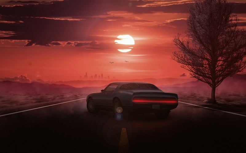 Car driving on road at sunset with city skyline