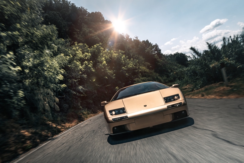 Gold Lamborghini Diablo driving on a winding road