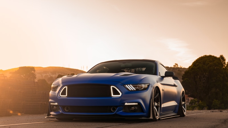 Blue Ford Mustang parked at sunset