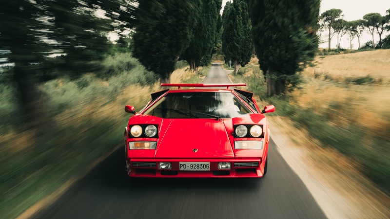 Red Lamborghini Countach driving on a road