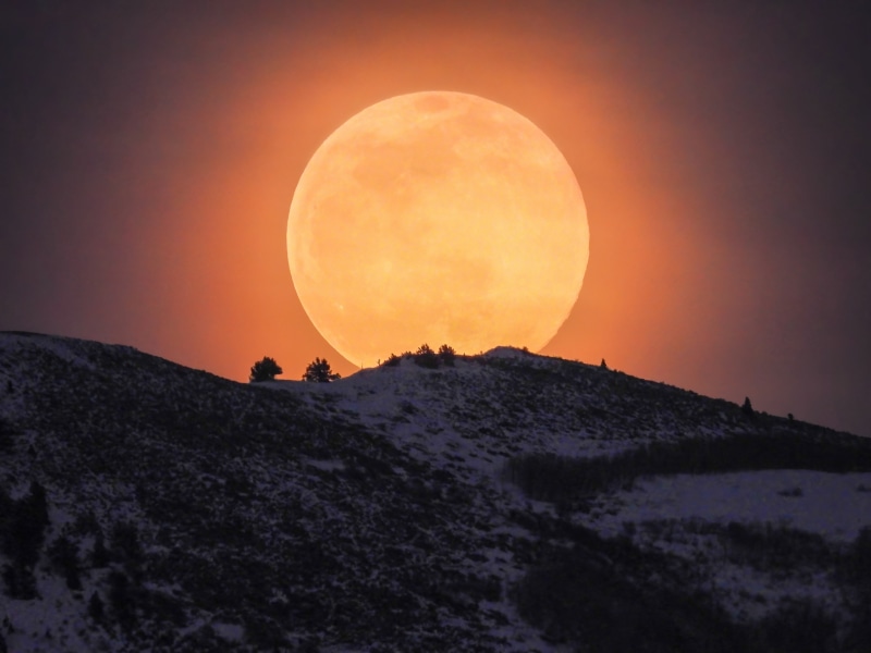 Full moon rising over snowy hills