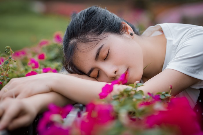 Peaceful Asian woman resting amidst vibrant pink flowers
