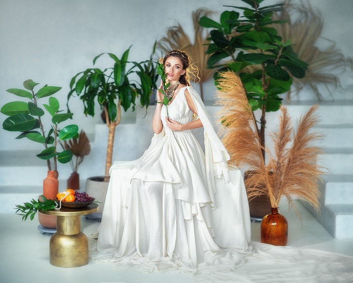 Elegant woman in white dress amidst lush plants