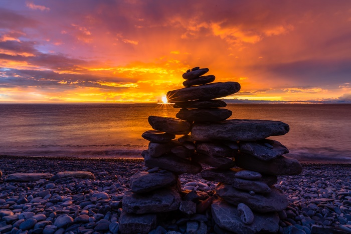 Vibrant Ocean Sunrise with Stone Cairn
