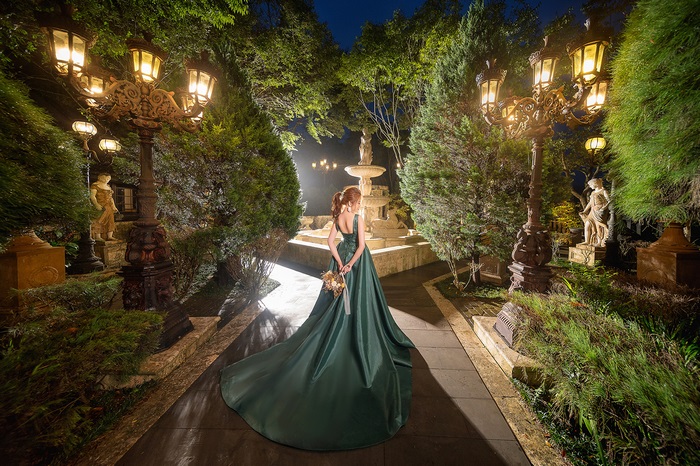 Asian model in green dress in illuminated garden