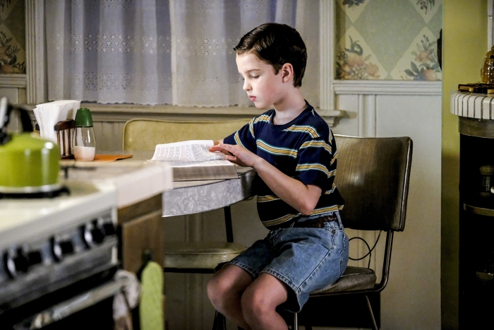 Young Sheldon Cooper reading a book at the table