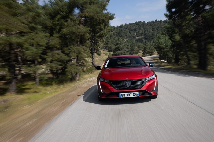 Red Peugeot 308 driving on a forest road