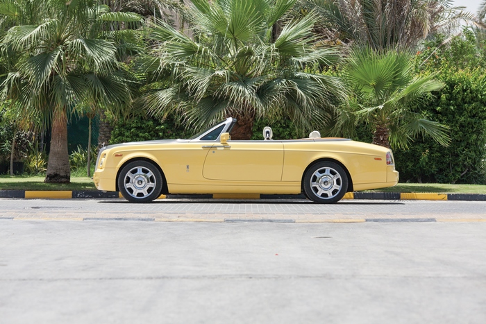Yellow Rolls-Royce Phantom Cabriolet parked under palm trees