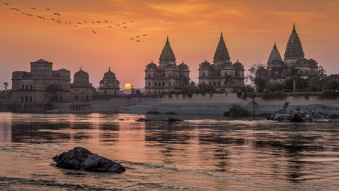 Majestic Orchha monuments reflected in river at sunset