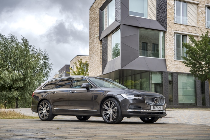Dark grey Volvo V90 luxury car by modern building