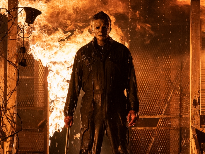 Michael Myers in a fiery inferno, holding a bloody weapon