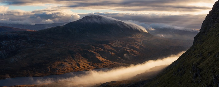 Golden light on mountain peak with flowing clouds and mist
