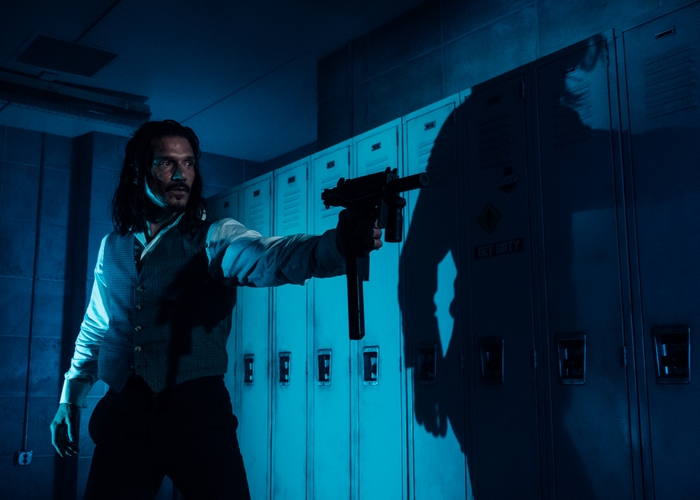 Frank Grillo holding a submachine gun in Copshop