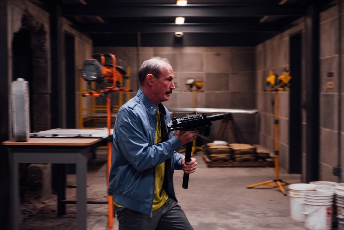 Toby Huss running with a gun in Copshop
