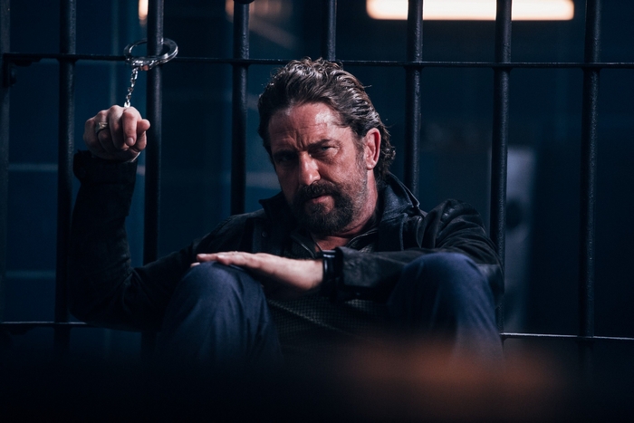 Gerard Butler in Copshop, behind bars with handcuffs