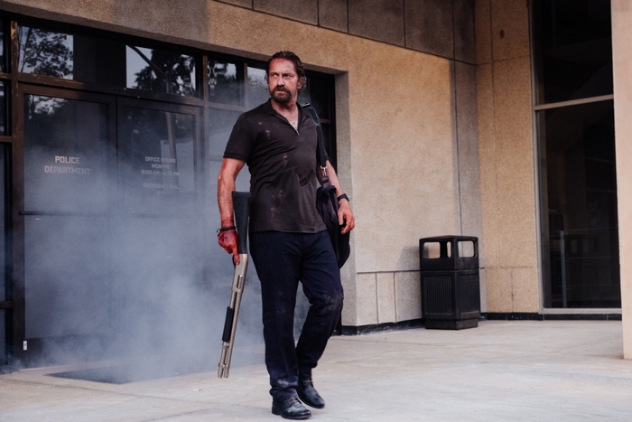 Gerard Butler in Copshop, bloody and holding a shotgun