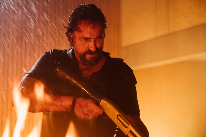 Gerard Butler, bloodied, holding shotgun in Copshop