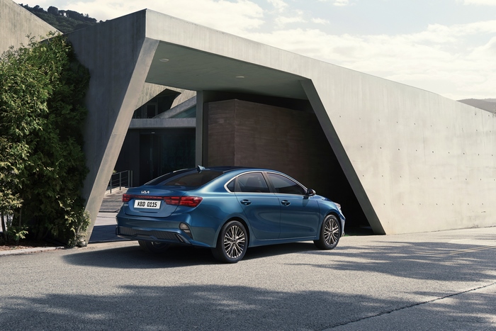Blue Kia Cerato 4K compact car by modern building