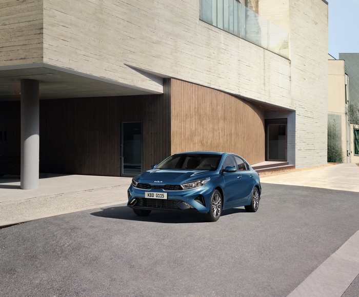Blue Kia Cerato compact car outside modern building