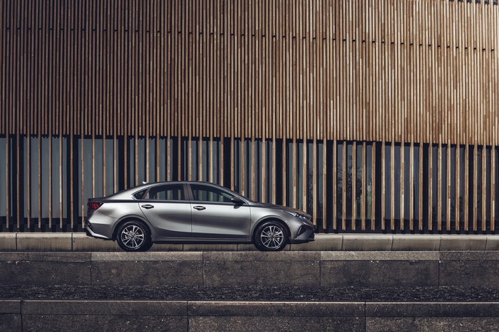 Silver Kia Cerato parked against modern wooden building