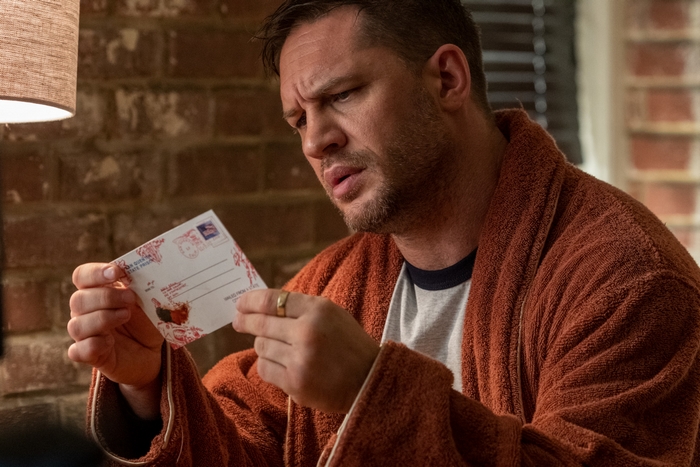 Eddie Brock looking at a postcard in Venom: Let There Be Carnage