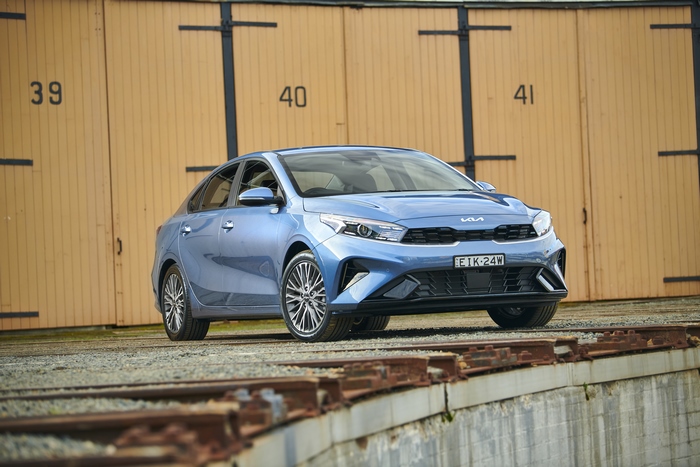 Blue Kia Cerato Sport Plus parked by numbered garages